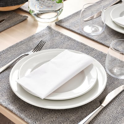 Dukning med SILVERARV vävda bordstabletter i bomull och jute, vit servis, glas och bestick.