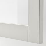 Närbild av SINDVIK ljusgrå skåp med front i klarglas, som visar upp elegant och modern design.