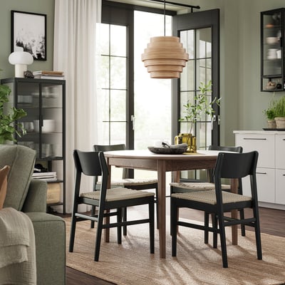 Modern matgrupp med utdragbart bord och svarta stolar. Rustik träfinish, rund form, naturliga accenter och elegant design.