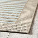 Plattvävd beige och blå matta på trägolv som visar upp kvalitet, struktur och design.