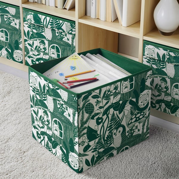 Förvaringsbehållare med grön design med naturtema rymmer ritpapper och kritor för barn.