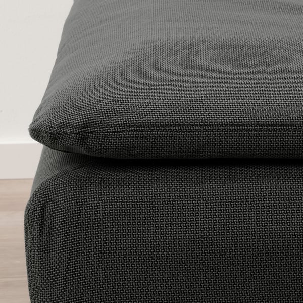 Mörkgrå klädd fotpall, texturerat tyg, hörnnärbild, modern design.