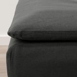 Mörkgrå klädd fotpall, texturerat tyg, hörnnärbild, modern design.