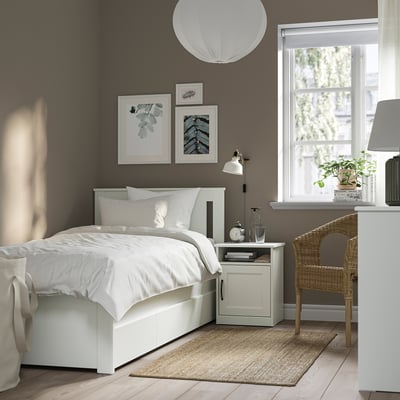 Minimalistiskt modernt sovrum med grå väggar, vit SONGESAND-säng, nattduksbord, korgstol och stort fönster.