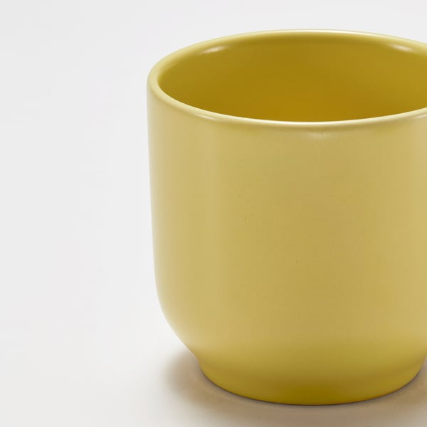 En närbild av en slät, ljusgul mugg som visar upp sin glansiga finish och breda öppning.