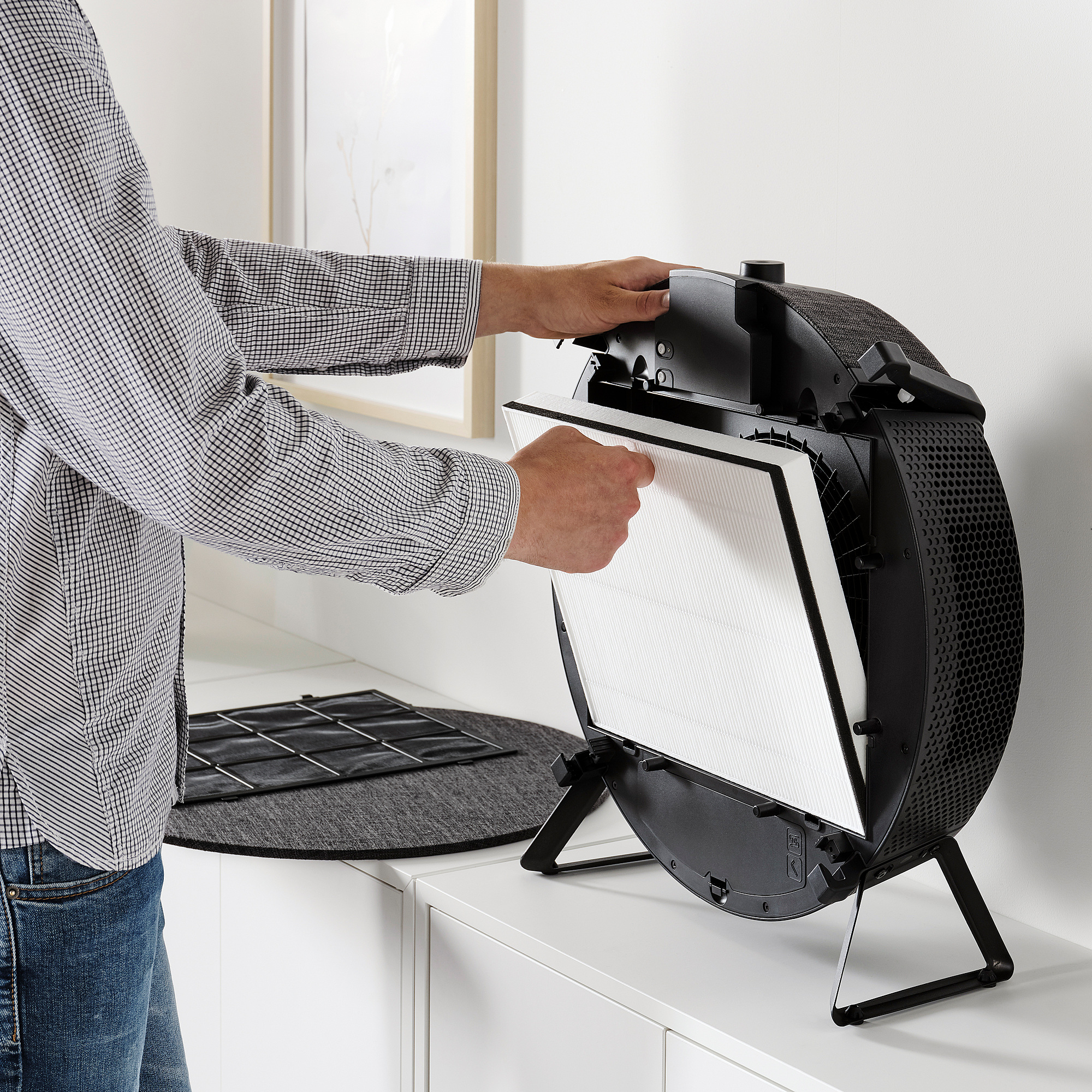 Personen installerar luftrenarens filter på en vit yta.