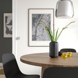 Modern mat: svart vas med gula blommor på träbord.