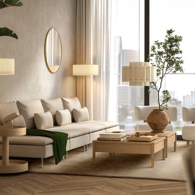 Modern minimalistiskt vardagsrum med stor beige sektionssoffa, soffbord i trä, stilfulla lampor och stadsutsikt.