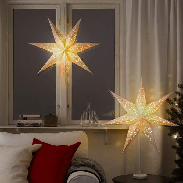 Mysigt vardagsrum med två upplysta stjärnformade lampskärmar, som skapar varm atmosfär, placerad på fönsterbrädan och bordet.