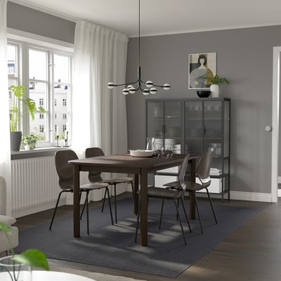 Modern matplats med utdragbart bord i mörkt trä, grå stolar och stort fönster.