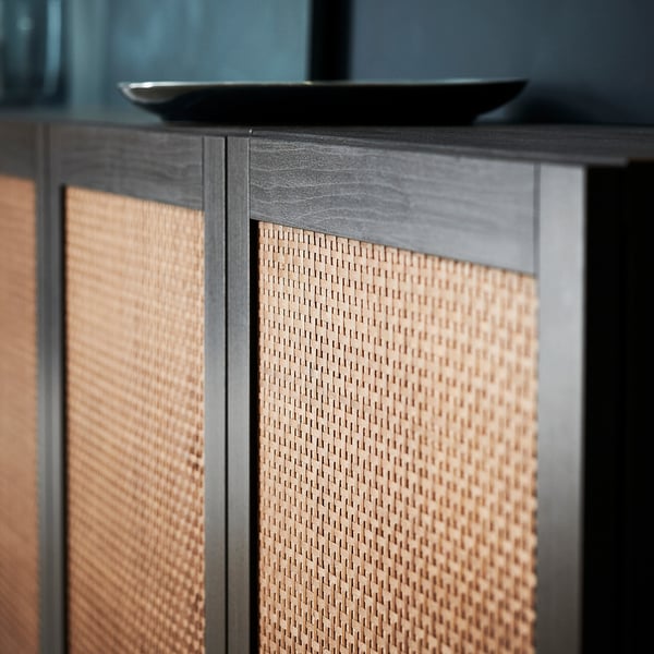 Vävda skåpdörrar i trä, svart inramning, strukturerade ytor. Modern design med naturliga toner.
