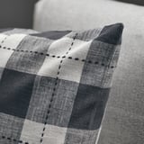 Svart och vitt: ett rutigt kuddfodral med svarta sömmar på en soffa, som visar upp dess kvalitetsstruktur och design.