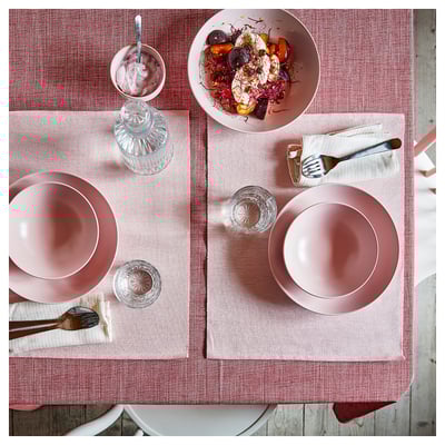 Rosa-röd duk av bomull, ställd med tallrikar, glas och mat på ett bord.