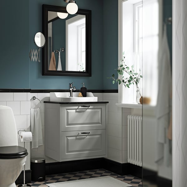 Ett modernt badrum med en TÄNNFORSEN grå kommod, med två lådor, ett handfat i keramik och en sammanhållen grå och vit design.