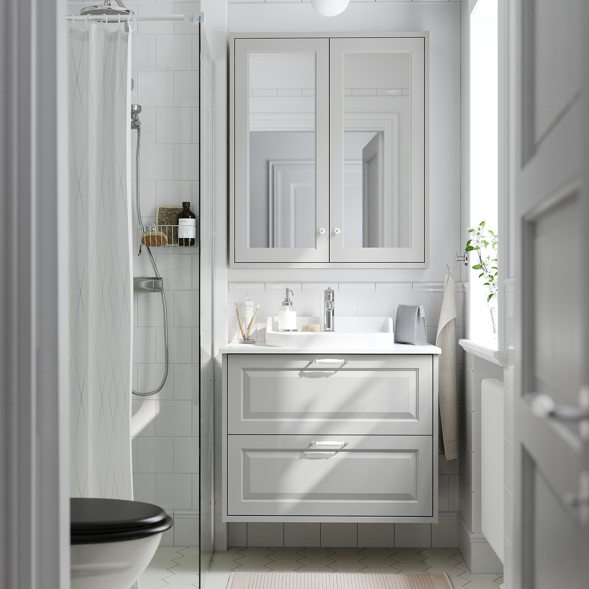 Modernt vitt badrum med TÄNNFORSEN ljusgrått skåp, halvinfällt handfat, spegel och dusch. Ren och rymlig design.