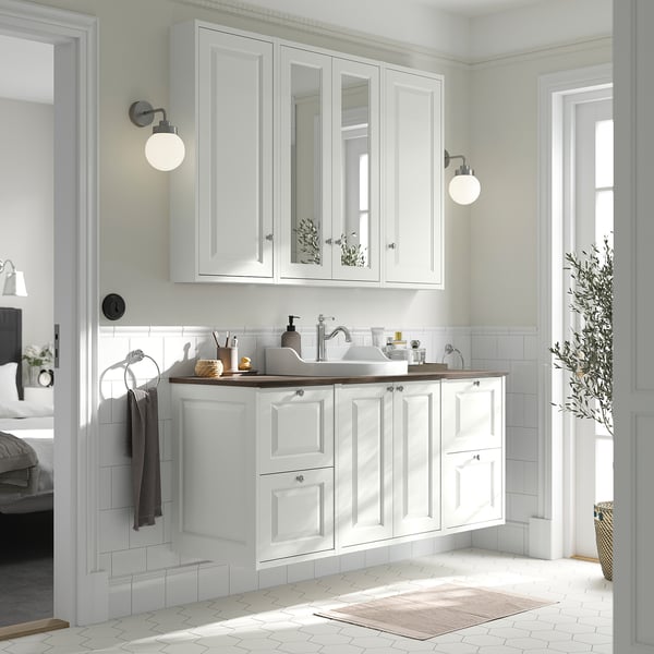 Modernt vitt badrumsskåp med spegel; bänkskiva, diskbänk och förvaring. Stor, väggmonterad, stilren design med knoppar.