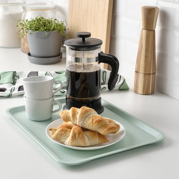 Grön bricka med bakverk, kaffe och vaskrens, inomhus/utomhus, tål diskmaskin. Eller en grön bakelsebricka med kaffe och vaskrens, som kan diskas i diskmaskin.