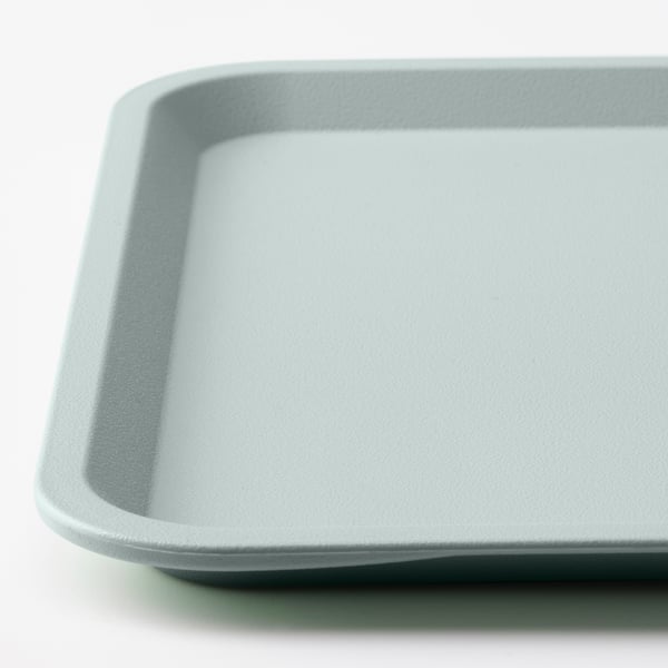 Ljusblå plastbricka med slät yta, vinklade kanter, inställd på vit bakgrund.