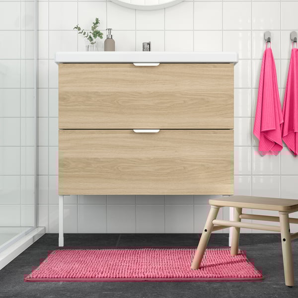Modernt badrum med handfat i ljust trä, rosa handdukar och TOFTBO badrumsmatta.