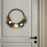 Krans av torkade blommor och växter hänger på en dörr och välkomnar besökarna med naturlig skönhet.