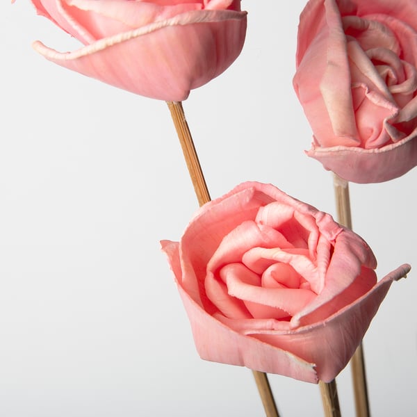 Tre delikata rosa rosor arrangerade, fint utformade och detaljerade.