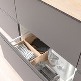 Öppen låda som visar köksförvaring med lådor för handdukar, svart tyg, mixer och brödrost.