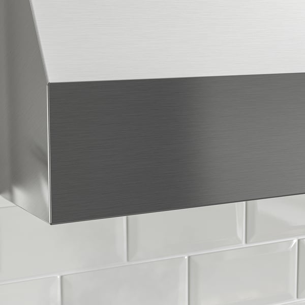 Köksfläkt i rostfritt stål, elegant design, monterad ovanför vitt kakel.