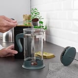 Häll kaffe för hand i den gröna maskinen på bänken.