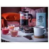 Kaffeuppställning med pressobryggare, ljus, choklad, kopp och ask på bordet.