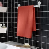 Orange handduk VÅGSJÖN på svart vägghylla i badrummet.