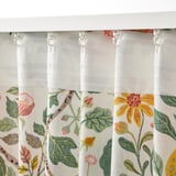 Blommiga gardiner med huvudtejp hänger från vita krokar, designade för att filtrera ljus och ge avskildhet med en avslappnad stil.