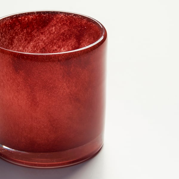 Elegant, handgjord ljusstake i rött glas med texturerad finish som reflekterar varma levande ljus.