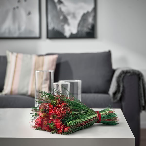 Mysigt vardagsrum med röda blommor, tall och vaser bredvid grå soffa, målningar.