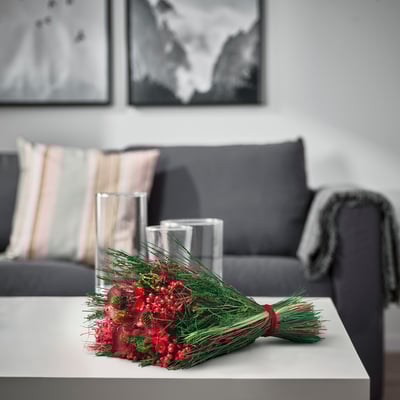 Mysigt vardagsrum med röda blommor, tall och vaser bredvid grå soffa, målningar.