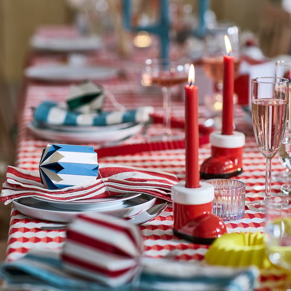 Elegant bordsdukning med röda ljus, randiga servetter, tallrikar och glas.