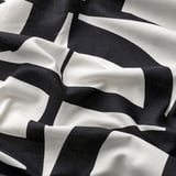 Abstrakt svart och vitt mönster på mjukt, texturerat tyg, skrynkligt för att visa textur och kvalitet.