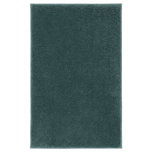 The BACKMÅRA bath mat is teal, rectangular, and thick with a textured, soft surface, made from recycled polyester and latex backing.