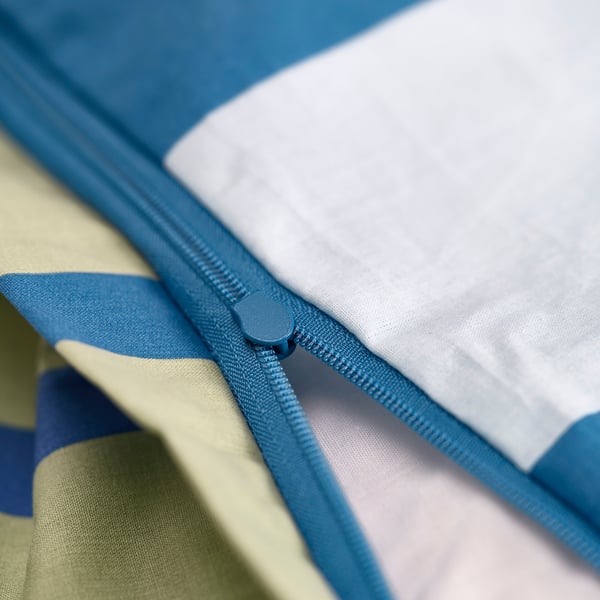 A close-up of a blue zip on a light blue and white blanket, showing its functionality.