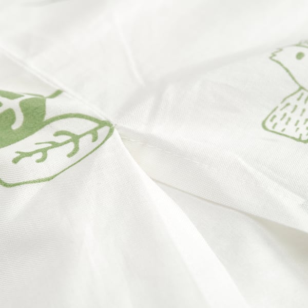 White fabric with green, stylized tree designs, suitable for children aged 3+.