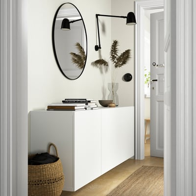 Modern minimalist hallway with BESTÅ storage, mirror, lamps, books, decor, and basket.