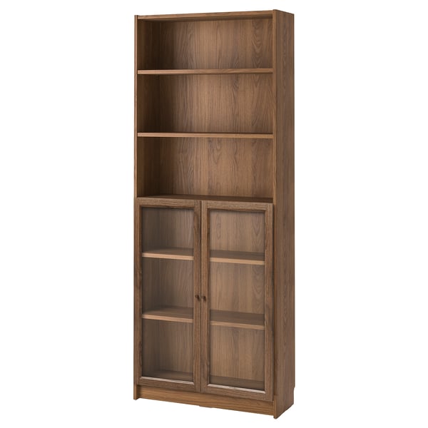 This image displays a wooden BILLY bookcase in brown with glass doors, featuring multiple shelves for storage.