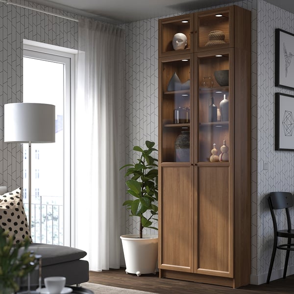 Modern living room with BILLY bookcase, patterned wall, cosy sofa, lamp, plant, and artwork.