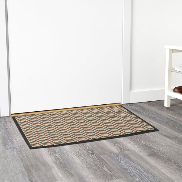 Door mat with wavy pattern and rubber backing against white door.