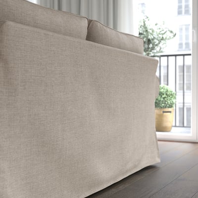 A beige EKTORP sofa by a window, with lush green plants outside. Soft, reversible cushions provide comfort and easy cleaning.