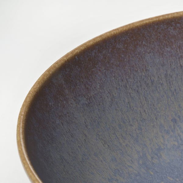 Close-up of rustic, handcrafted stoneware bowl; deep blue glaze with subtle streaks.