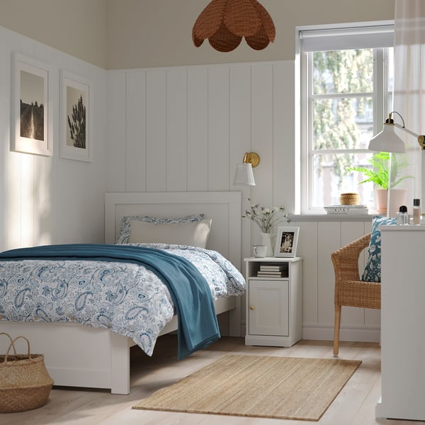 Bedroom with FÅGELFJÄLLET bedside table, blue bedding, large window.