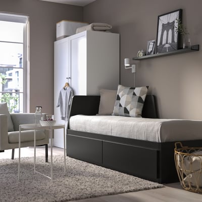 Modern grey FLEKKE sofa-bed near large window. Its smaller than the wardrobe, fits well in compact rooms.