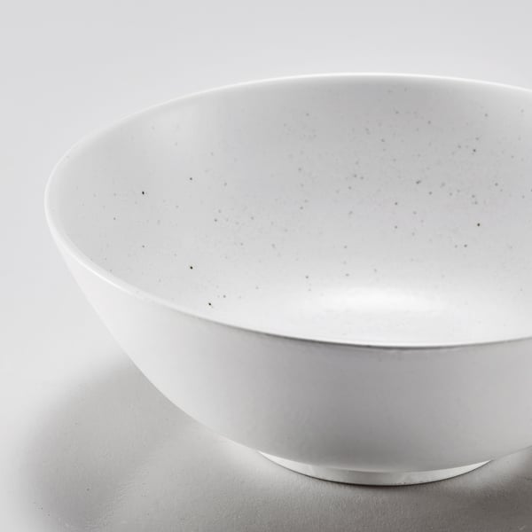 White porcelain bowl with subtle glaze texture, smooth edges, resting on a reflective surface.