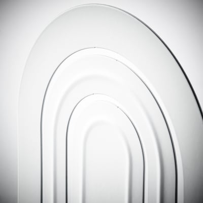 A white HÖSSLA bookend. Its arched, made of epoxy-coated steel, and has vertical grooves on its front.