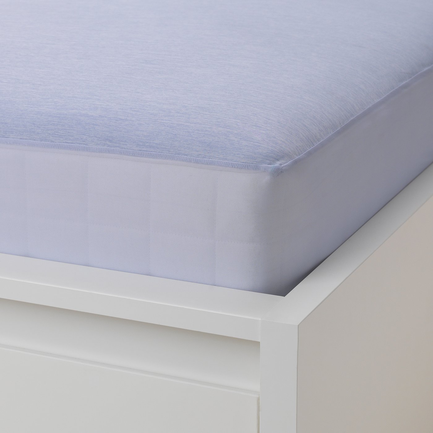 A fitted light blue sheet on a white bed frame, designed to fit mattresses up to 26 cm thick.